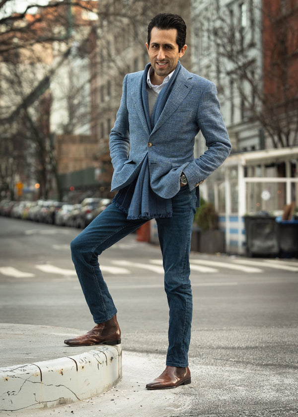Man in a blue blazer and jeans standing on a city street.