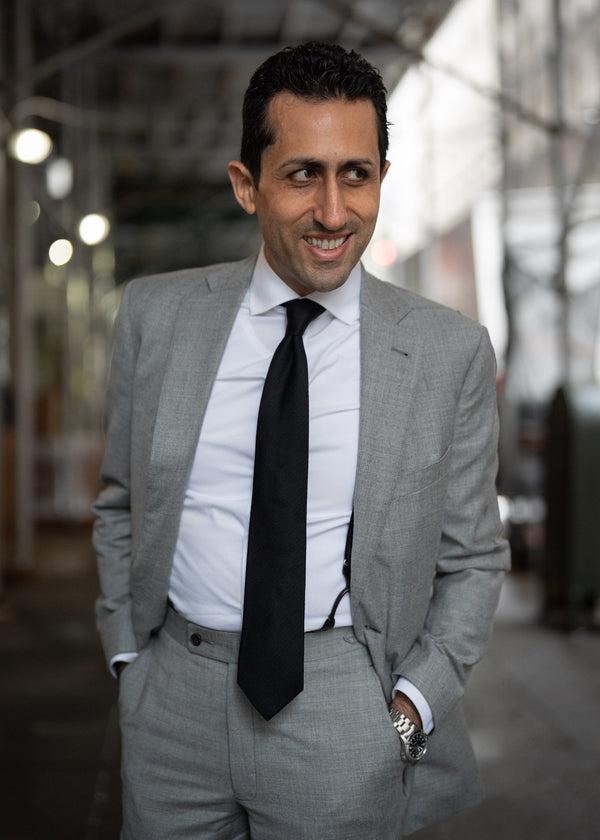 Man wearing a gray suit with a black tie in an urban setting