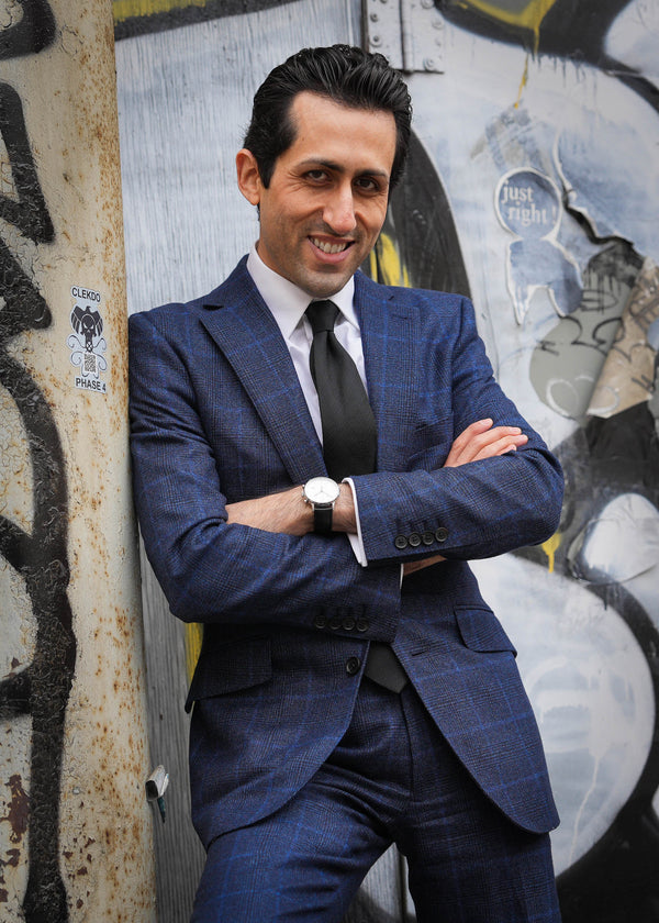 Man in a blue suit standing against a graffiti-covered wall