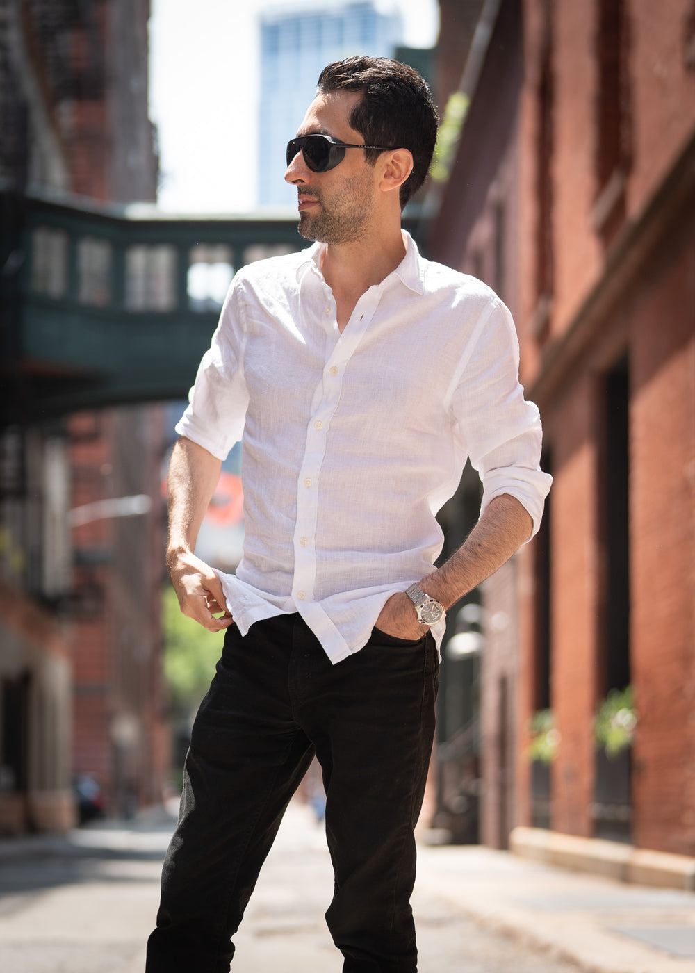 Man wearing a white shirt and sunglasses on a city street.