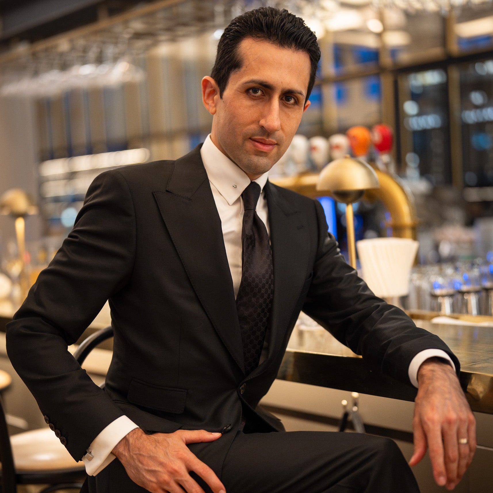 Man in a suit sitting on a bar stool in a modern bar setting