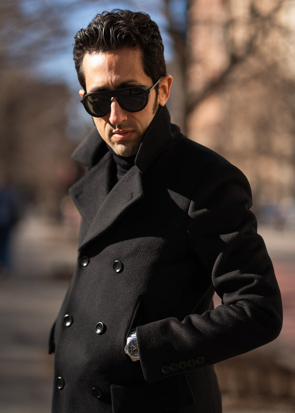 Man wearing a black coat and sunglasses outdoors