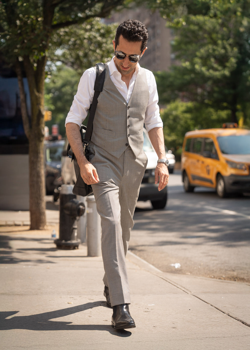 Man in a suit walking on a city street with a taxi in the background
