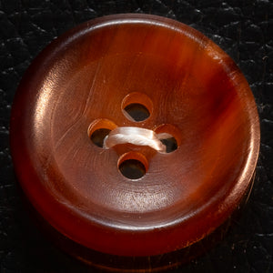 Brown button with three holes on a dark textured background