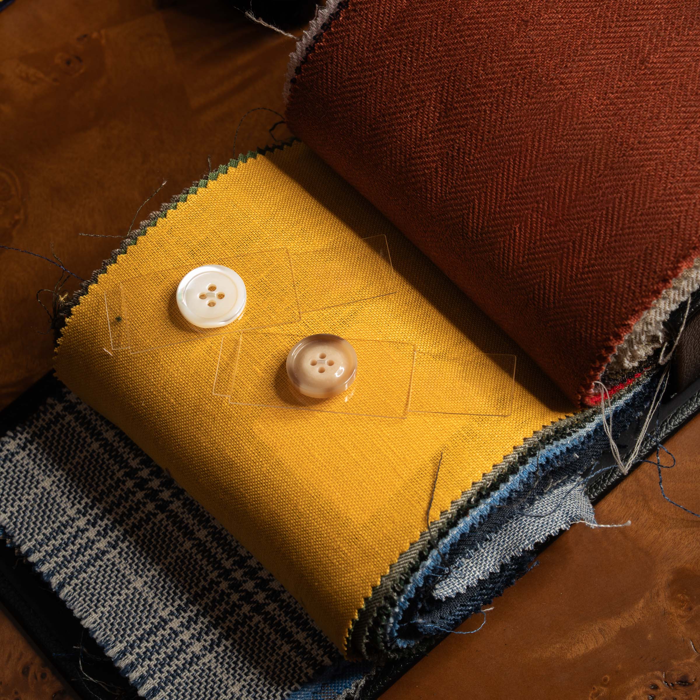 Yellow fabric swatch with buttons on a textured surface