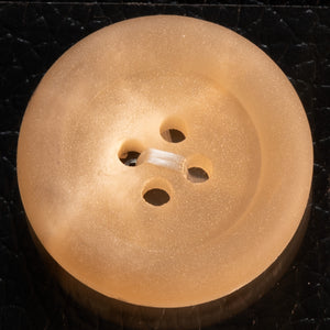 Beige button with three holes on a black background