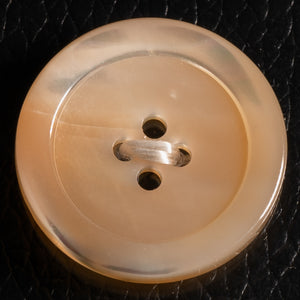 Beige button with two holes on a black textured background