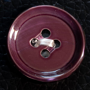 Close-up of a purple button on a textured black background
