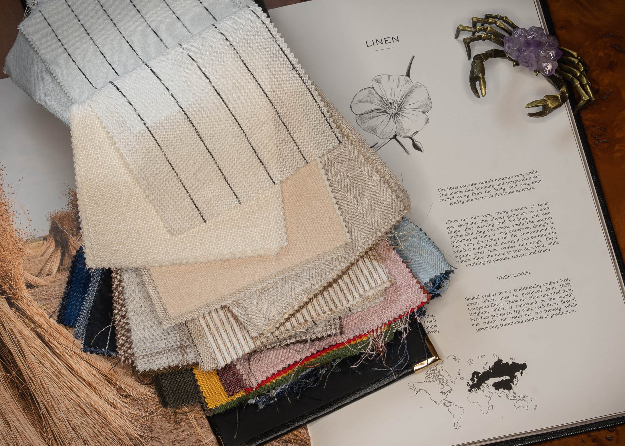 Color swatches of linen fabric next to an open book on a wooden surface