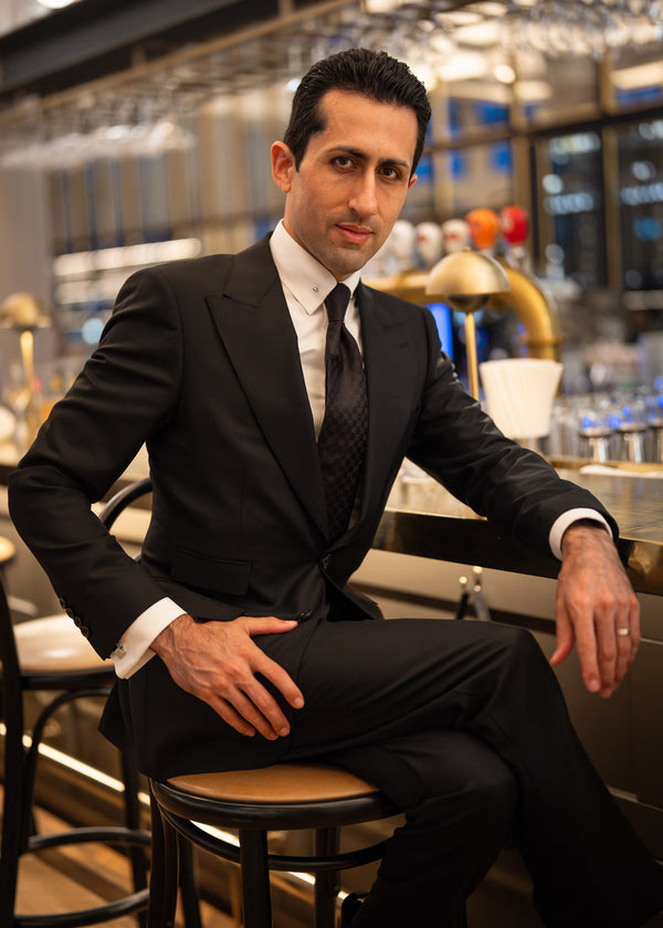 Man in a suit sitting on a bar stool in a modern bar setting