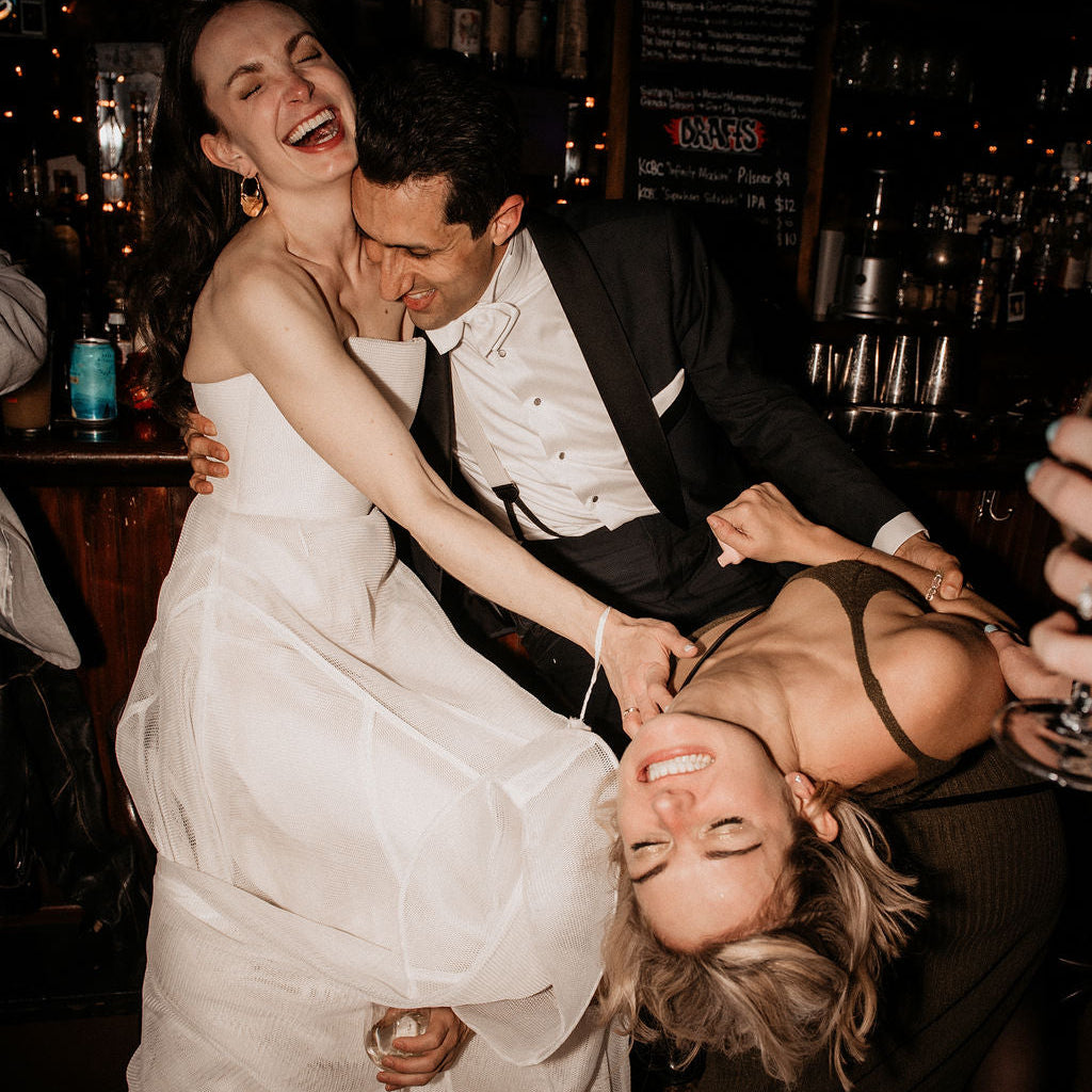 Two people in formal attire celebrating in a bar setting.