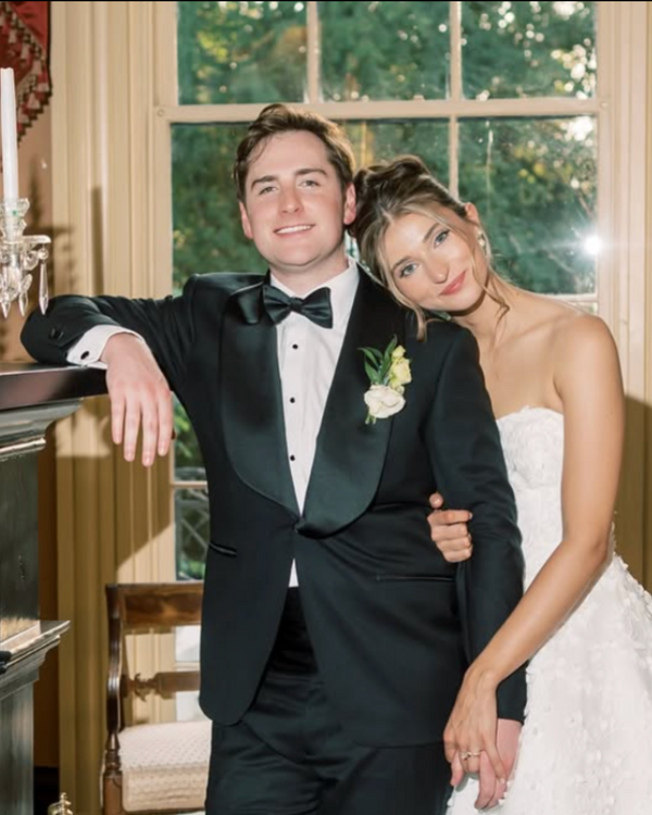 Man in tuxedo and woman in wedding dress posing in a decorated room.