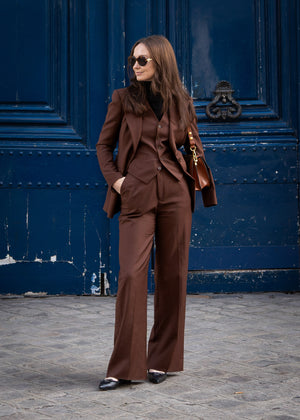 Woman in a brown suit standing in front of a blue door.