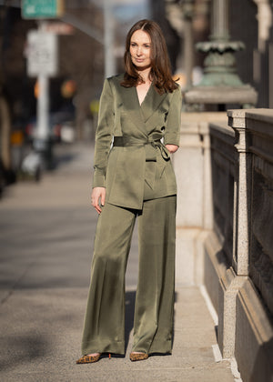 Woman in a green suit standing on a city street.